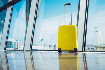 isolate traveler tourist yellow suitcase at floor airport on background large window, bright luggage waiting in departure lounge area hall of ​airport lobby terminal, vacation trip concept, empty 
