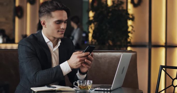 Young businessman working in cafe. Freelancer using smartphone and laptop. Successful busines, IT, Freelancer concept.