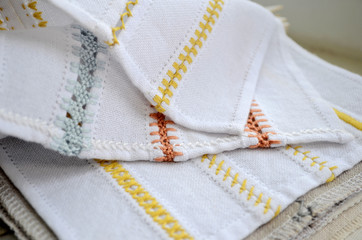 Different yellow, orange and blue patterns of embroidery on white fabric