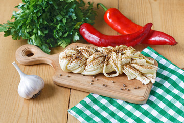 Cheese on wooden board, spices, greens, chili, garlic on a wooden background. Sulguni cheese