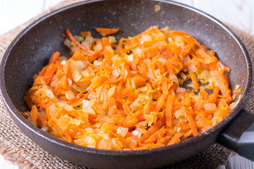 onion rings and carrots stew in a hot pan, close-up