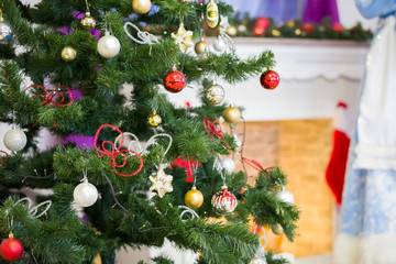 Fragment of a Christmas tree with toys on the background of an artificial fireplace.Christmas background