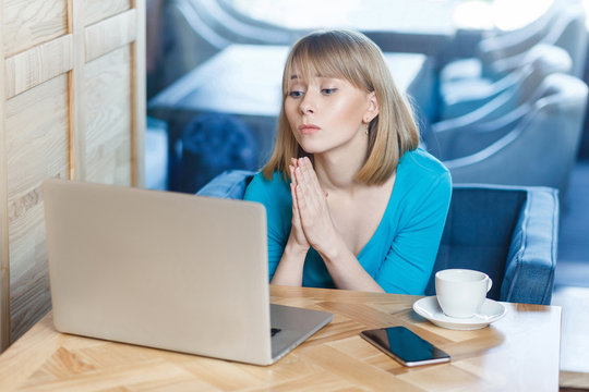 Please help me! Portrait of young beautiful student with blonde hair in blue t-shirt sitting in cafe and talking thought webcame with group mate begging for help with her homework