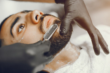 Naklejka premium The man cuts his beard in the barbershop
