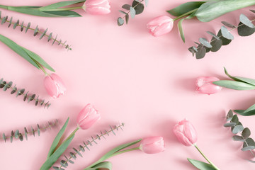 Plakat Flowers composition romantic. Pink flowers tulips, eucalyptus leaves on pastel pink background. Frame made of eucalyptus branches and tulips. Flat lay, top view, copy space