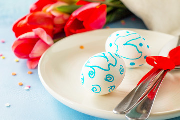Easter table setting with tulips flowers and cutlery on stone table. Holidays background.
