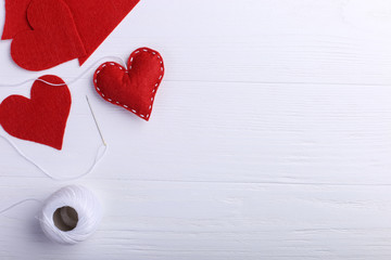 Handmade red felt heart next to threads and a needle on a white table. Women's Day Concept, Copy...