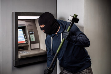 Thief destroys a sledgehammer ATM. Сoncept of crime and law violation