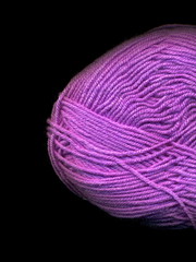Skein of colored yarn on a dark background.. Skein of purple yarn.