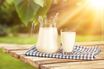Glass of milk and jug on blurred background