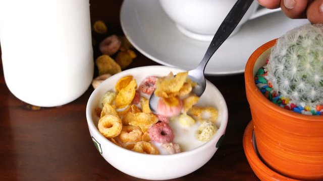 Scooping and eating cereal Corn Flakes and Froot Loops from a white bowl as a breakfast