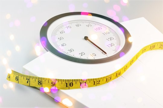 Bathroom scale with a measuring tape on background