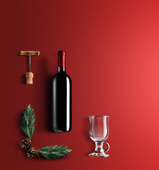 Mulled wine recipe ingredients and kitchen accessories, bottle of red wine, cinnamon, anise stars, orange, brown sugarand spice on red background.