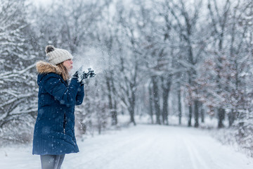 woman blowing handful of snow into the air in winter wonderland