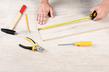 Man installing timber laminate flooring with tools