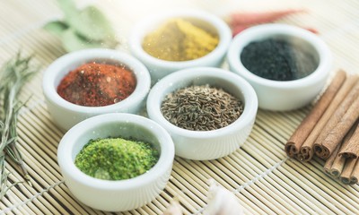 Various colorful spices in bowls on wooden table