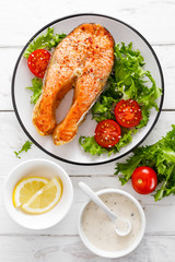 Salmon fish steak grilled and fresh vegetable salad with tomato and lettuce. Healthy food. Top view