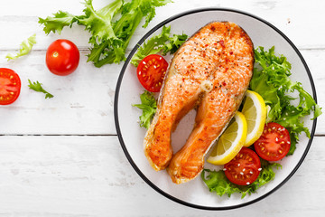 Salmon fish steak grilled and fresh vegetable salad with tomato and lettuce. Healthy food. Top view