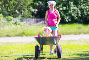 Girls playing  with wheelbarrow in the garden