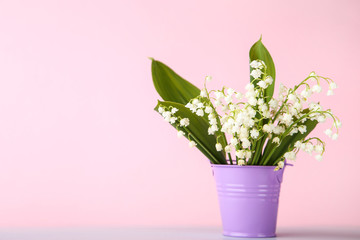 Lily of the valley flowers in bucket on pink background