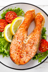 Salmon fish steak grilled and fresh vegetable salad with tomato and lettuce. Healthy food. Top view