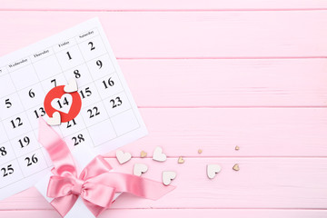 Valentine day calendar with hearts and gift box on wooden pink table