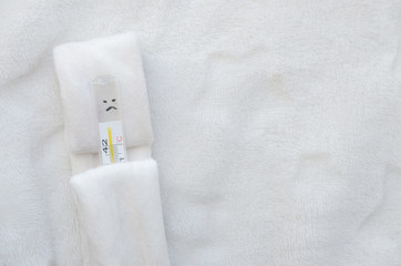Obraz na płótnie Canvas Thermometer on a pillow under a blanket on a white background.
