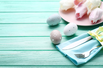 Kitchen cutlery with easter eggs and tulip flowers on mint wooden table