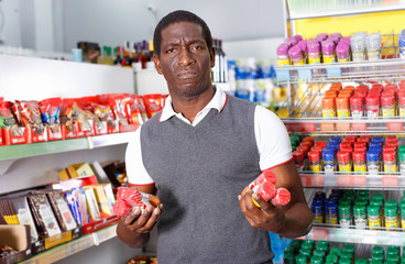 Positive African man choosing spice in grocery store