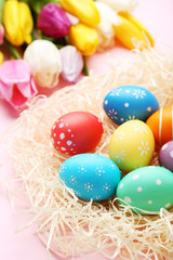 Fototapeta na wymiar Colorful easter eggs in nest on pink background