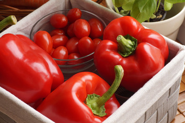 Peppers, tomatoes and basil in a pot. A kitchen basket filled with vegetables.