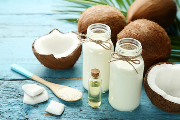 Coconut milk in bottles with oil and flakes on blue wooden table