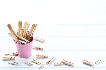Obraz premium Brown clothespins in pink bucket on wooden table