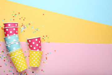 Paper cups with confetti on colorful background