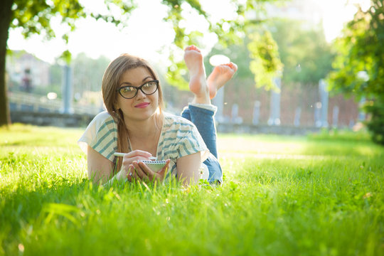 Dreaming young woman with her diary in a park