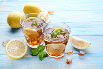 Ice tea in glasses with lemon and mint leafs on wooden table