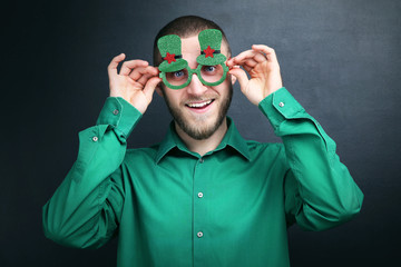 St. Patrick's Day. Young man wearing green glasses on black background