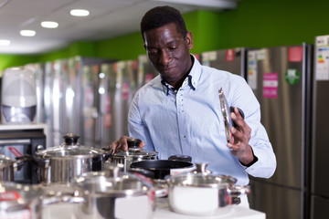 Man chooses saucepan in store of household appliances