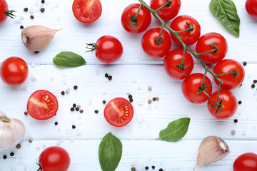 Cherry tomatoes with basil leafs, garlic and spices on wooden table