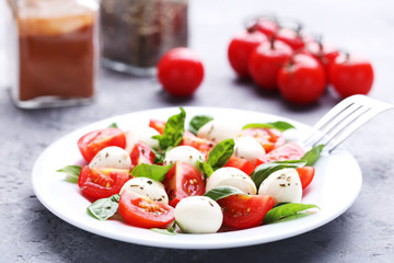 Mozzarella, tomatoes and basil leafs on grey wooden table