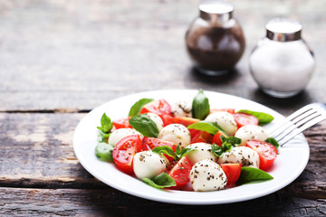 Mozzarella, tomatoes, basil leafs with salt and pepper on wooden table