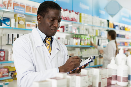 Man  specialist of pharmacy making notes on clipboard