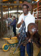 Farm workers preparing horse harness