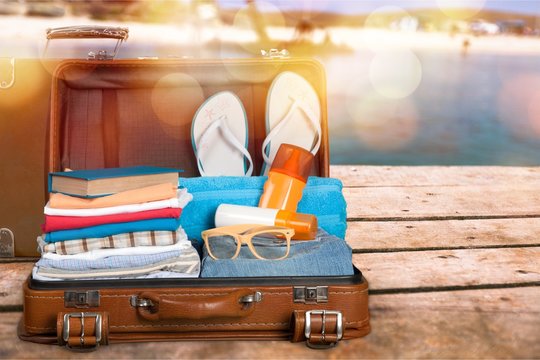 Retro suitcase with travel objects  on sea background