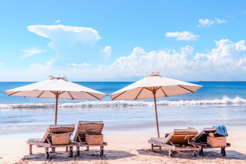 Beach with chairs. Sunbeds and umbrella at Bali coast. Luxury beach background. Dreamlike romantic landscape. Concept of an ideal tropic exotic vacation.