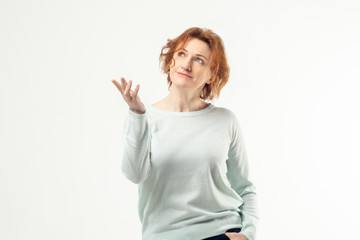Elegant aged mature red haired woman looking up with dreamy and happy expression on her face and holding her right hand against white background