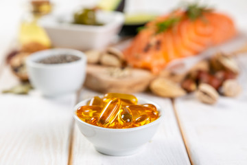 Selection of healthy unsaturated fats, omega 3 - fish, avocado, olives, nuts and seeds Vs pills