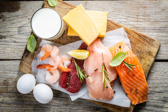 Selection of aminal protein sources - beef, chicken, salmon, cheese, milk, eggs, shrimps on wood background