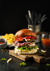 Tasty burger with bacon and chilli peppers with fries and ketchup