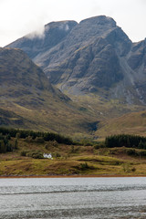 Fototapeta na wymiar Isolated house on Isle of Skye with mountain and clouds in background - Scotland